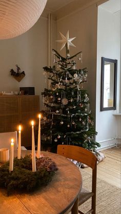 a small christmas tree with lit candles in front of it on a dining room table