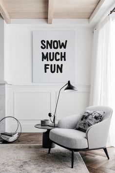 a living room with a chair, lamp and poster on the wall above it that says snow much fun