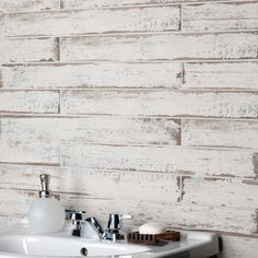 a white sink sitting next to a wooden wall