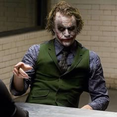 a man dressed as the joker pointing at another person with his finger in one hand