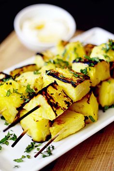 pineapple skewers with parsley on a white plate