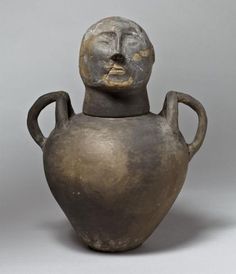 a bronze colored vase with a face on it