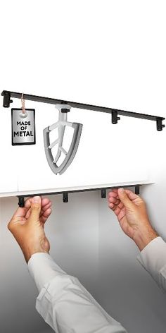 two hands are pulling the metal bar from the wall