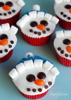 some cupcakes with frosting and icing on them are decorated like a snowman