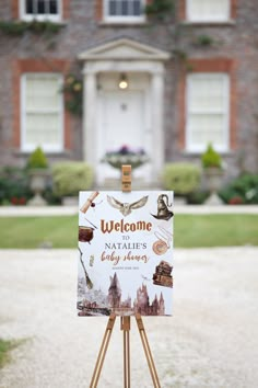 a welcome sign stands in front of a large brick building with an ornate door and windows