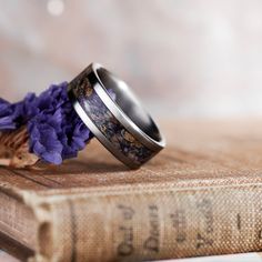 two wedding rings sitting on top of an old book with purple flowers in the middle