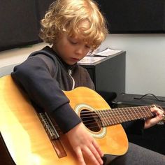 a young boy is playing an acoustic guitar