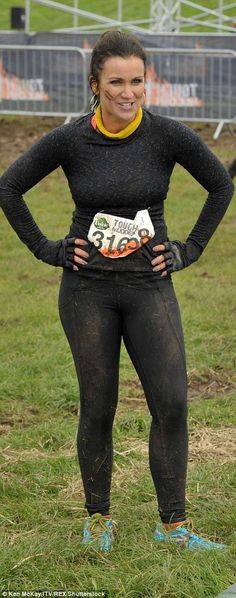 a woman standing in the grass with her hands on her hips and wearing wetsuits