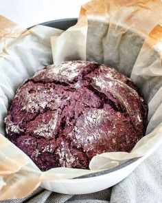 a loaf of bread sitting inside of a pan on top of a cloth covered table