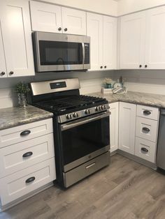 a kitchen with white cabinets and silver appliances