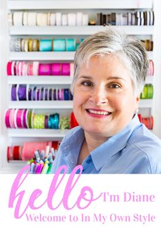 a woman standing in front of a wall with lots of spools of thread