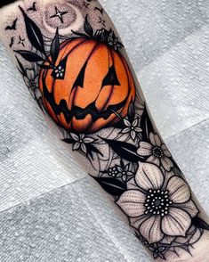 a black and white tattoo with an orange pumpkin on it