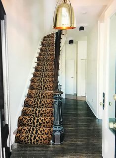 the stairs are lined with leopard print rugs and a light fixture is hanging above them