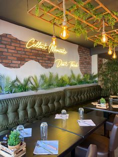 an empty restaurant with green plants on the wall