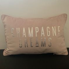 a pink pillow that says champagne dreams on the front and back of it, sitting on top of a black table