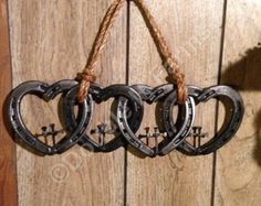 three horseshoes hanging from a rope on a wooden wall with two hearts attached to them