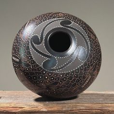 a black vase sitting on top of a wooden table