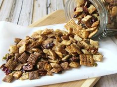 a pile of cereal sitting on top of a white plate next to a glass jar