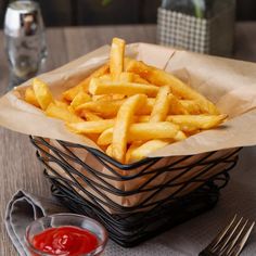 a basket filled with french fries sitting on top of a table next to ketchup