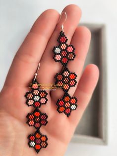 a hand is holding some small beaded earrings