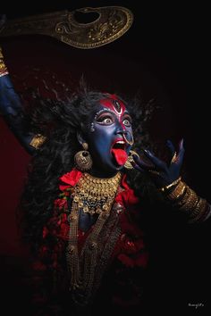 a woman dressed in blue and red with her hands up to the side, holding an object above her head