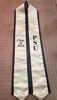 a white and black tie laying on top of a wooden floor with the words class of 202 printed on it