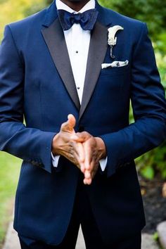 a man in a tuxedo holding his hands together