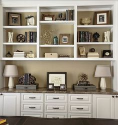 a living room filled with lots of white furniture and bookshelves on top of each other