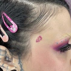 a close up of a woman's face with tattoos on her forehead and eyeliners