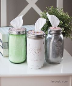 three mason jars with tissue paper in them sitting on a table next to a book