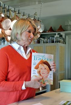 a woman is reading a magazine in the kitchen