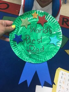 a child holding up a paper plate with the words world's best dad written on it