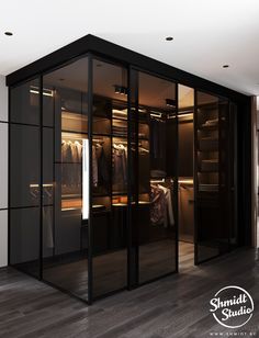 a walk in closet with glass doors and clothes hanging on hangers next to it