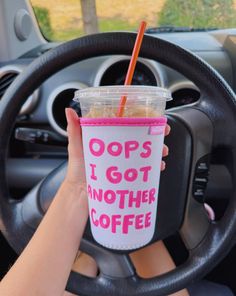 a person holding up a cup with a straw in it while sitting in a car