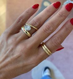 a woman's hand with red nails and two rings on her fingers, one ring has a diamond in the middle