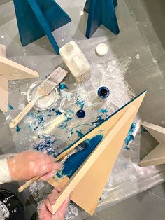 a person is working on some art work with blue paint and wooden dows in front of them