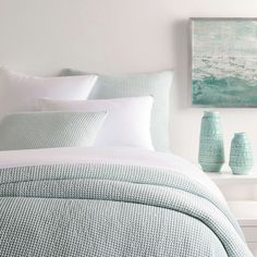 a bed with white sheets and blue vases