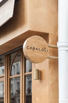 a wooden sign that reads caracoli on the side of a building with glass windows