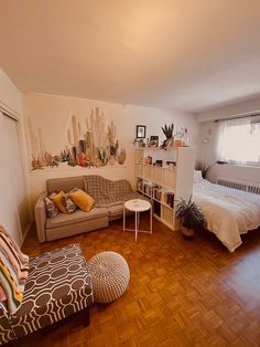 a living room filled with furniture next to a bed and a wooden floor covered in pillows