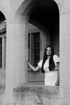 black and white photograph of a woman standing on a balcony with her hands in the air