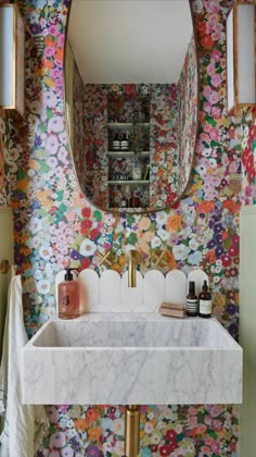 a bathroom with floral wallpaper and marble sink