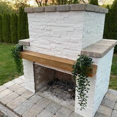 a white brick fireplace with a wooden mantle and plant growing on the top shelf next to it