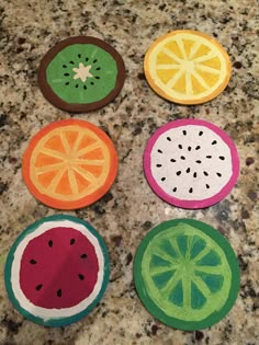 four slices of fruit painted on top of a granite countertop, each with different colors