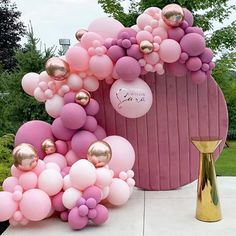 balloon arch with pink and gold balloons in front of a large potted planter