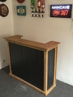 a small wooden bar in the corner of a room with several signs on the wall