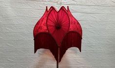 a red umbrella is hanging on a white brick wall