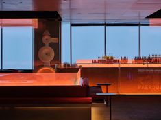 an empty restaurant with lots of bottles on the counter and tables in front of large windows