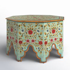 an ornately painted stool with flowers and leaves on the top, sits against a white background