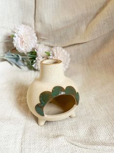 a white vase sitting on top of a table with flowers in the backround