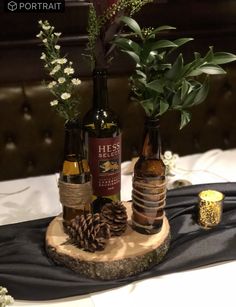 three wine bottles are sitting on a table with pine cones and greenery in them